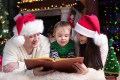 Friendly family reading book under the Christmas tree on xmas evening