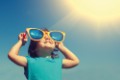 Happy little girl with big sunglasses  looking at the sun